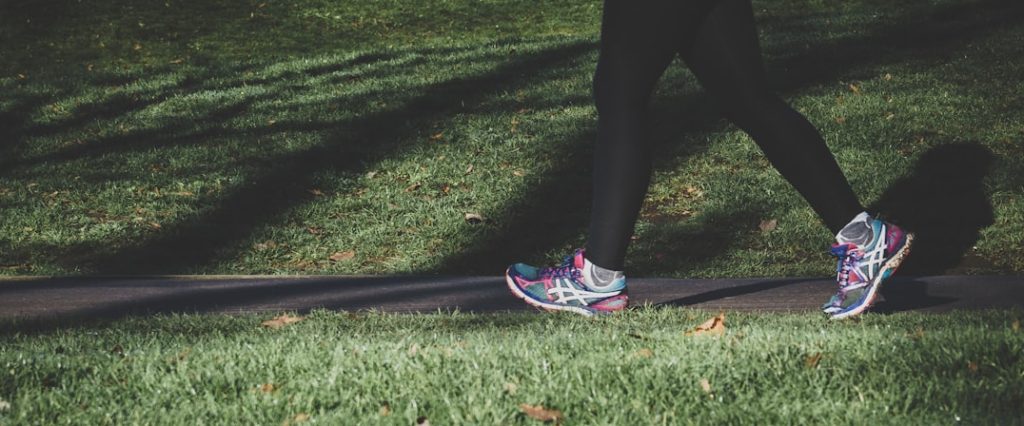 shallow focus photography of person walking on road between grass